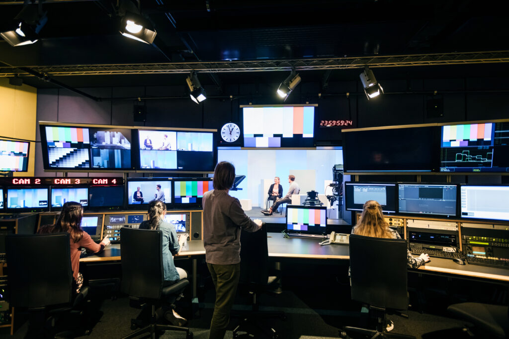 A group of university students working in a tv studio and learning how to use the equipment.