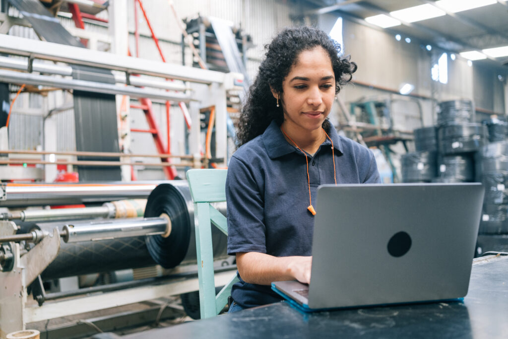 Engineer working on laptop in plastic recycling factory